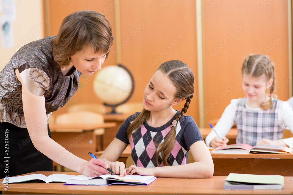 Schoolkids work at lesson. Teacher controling learning process. Schoolkids work at lesson. Teacher controling learning process.