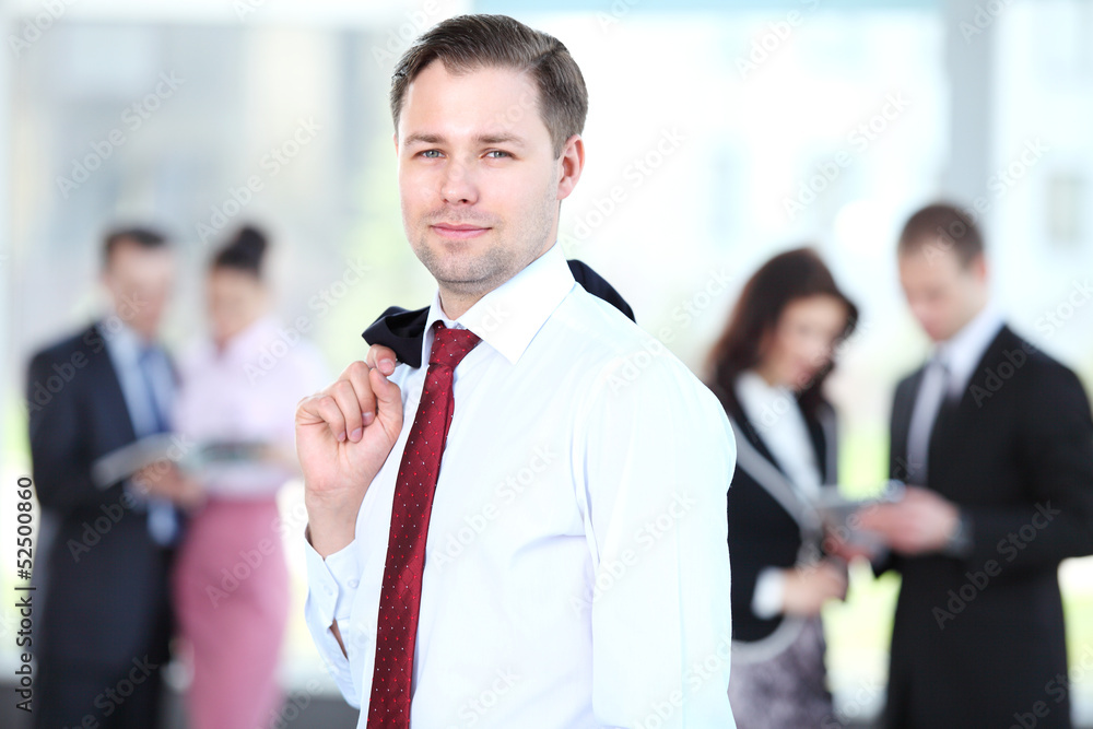 Handsome happy business man with colleagues at the back Handsome happy business man with colleagues at the back