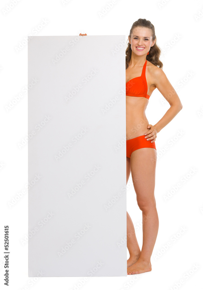 Happy young woman in swimsuit showing blank billboard Happy young woman in swimsuit showing blank billboard