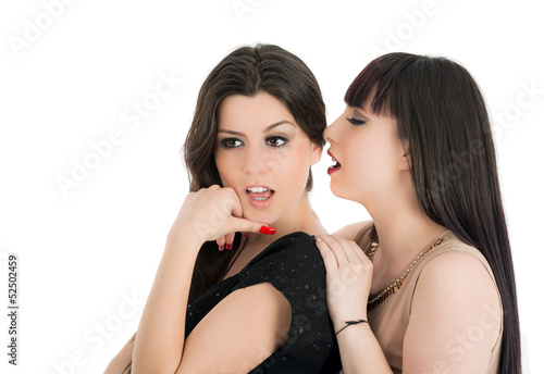 Two young girlfriends sharing their secrets, studio shot