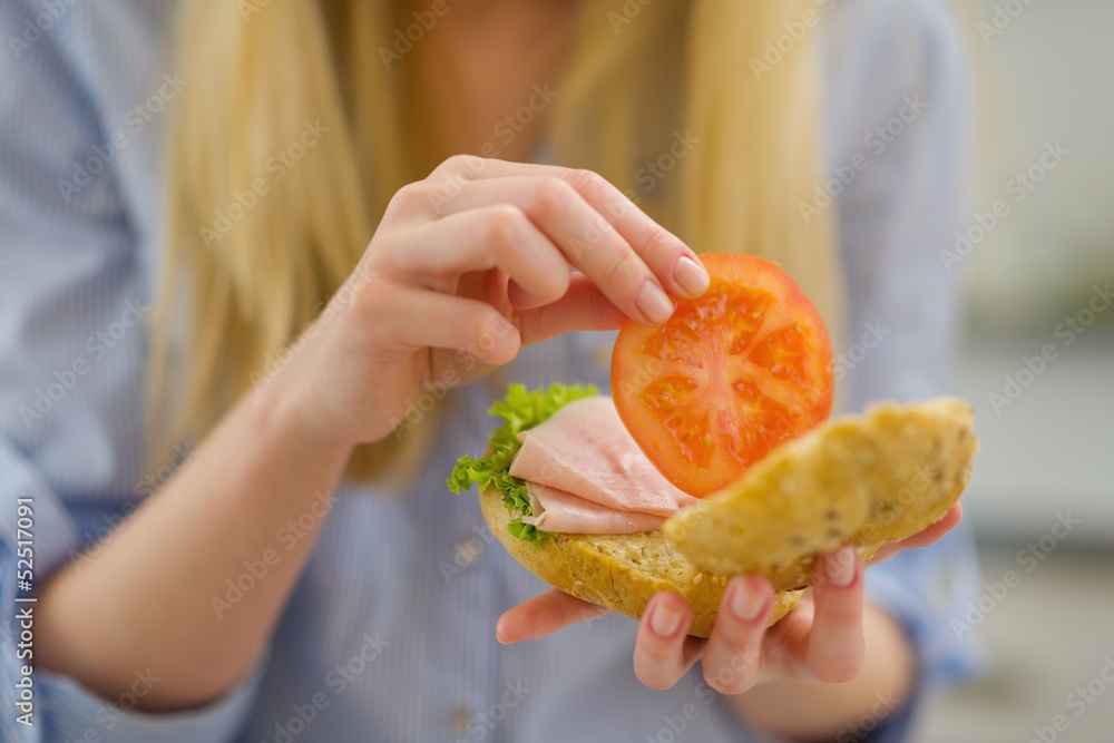 Closeup on young woman making sandwich in kitchen