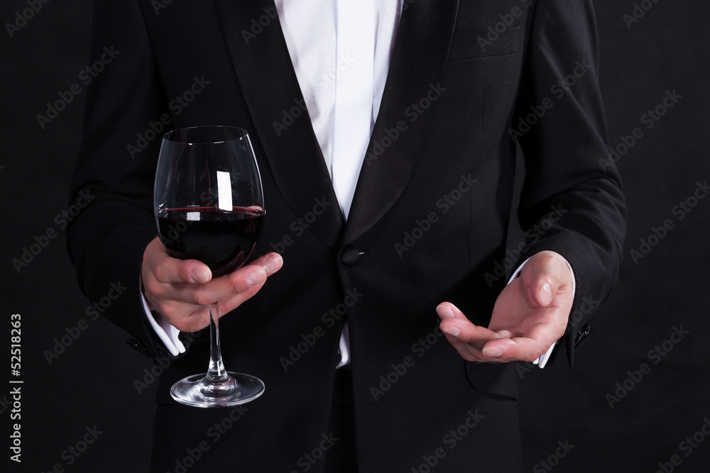 Fragment of stylish man in elegant black tuxedo with glass red w Fragment of stylish man in elegant black tuxedo with glass red w