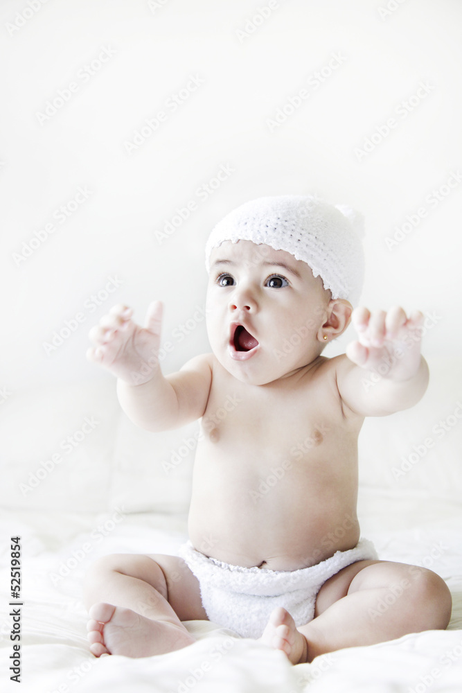 baby girl siting on the bed with expression of surprise baby girl siting on the bed with expression of surprise