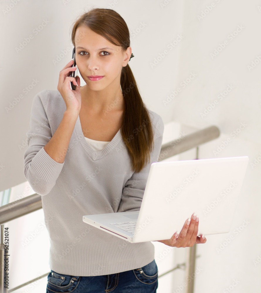 woman holding on laptop and talking on the phone woman holding on laptop and talking on the phone