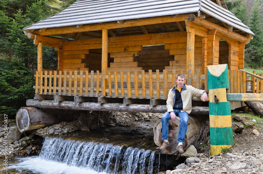 Man sitting at a hut built over a waterfall Man sitting at a hut built over a waterfall