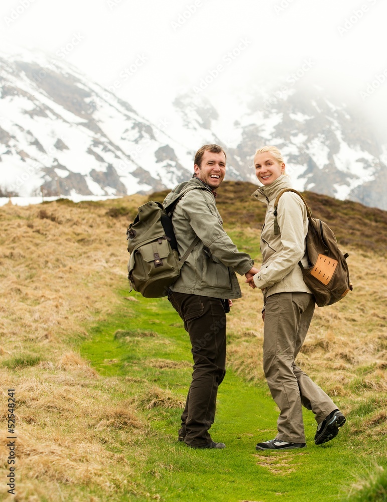 Happy young hiker couple with backpacks in mountains Happy young hiker couple with backpacks in mountains