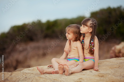 Canvas Print two sisters sitting on a rock and looking into the distance