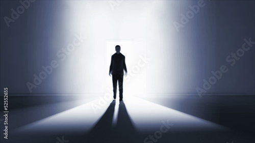 Man walking in a dark room with light coming from behind