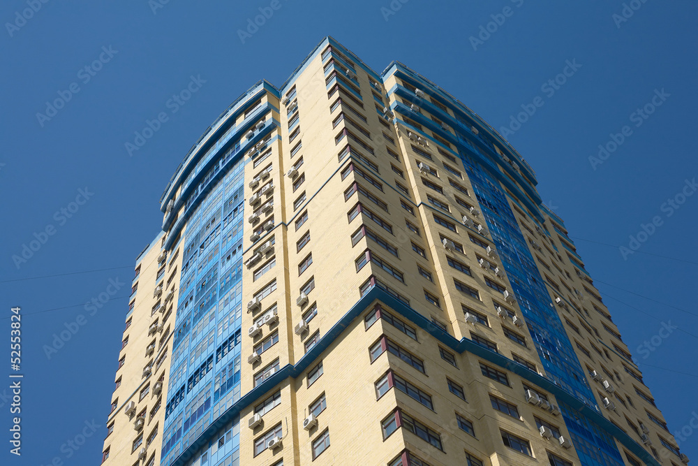 High yellow modern residential building on blue cloudless sky