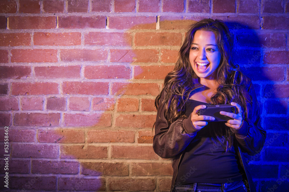 Mixed Race Woman Using Her Cell Phone Against Brick Wall