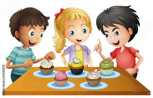 Three kids at the table with cupcakes