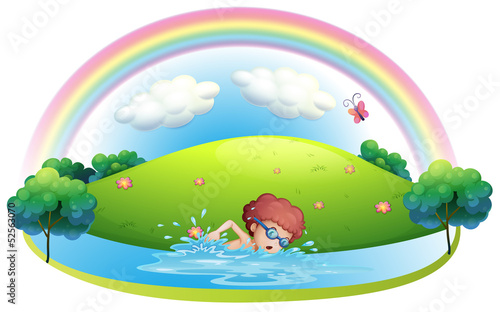 A young man swimming near the hill with a rainbow