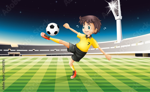 A boy in his yellow uniform playing soccer at the field