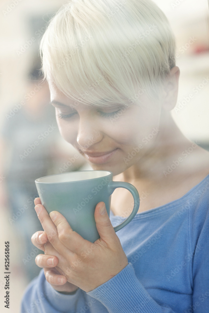 Attractive woman enjoying her coffee behind a window Attractive woman enjoying her coffee behind a window