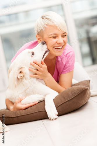 Bild auf Leinwand Dog is giving a kiss to a smiling woman