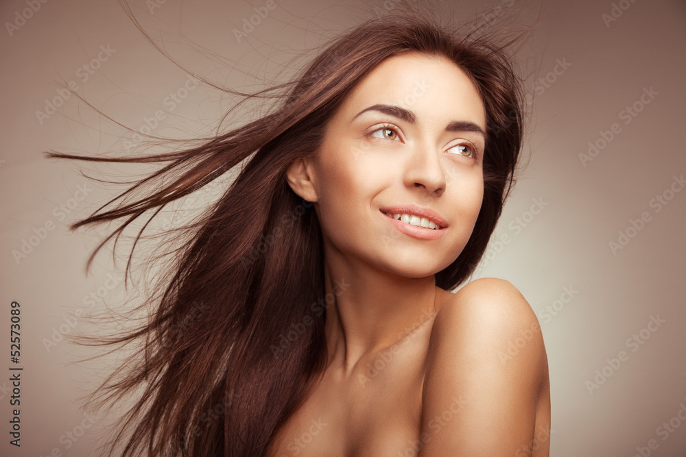Attractive smiling woman with long hair on grey