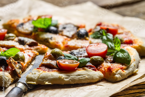 Closeup of baked pizza with olives and tomatoes