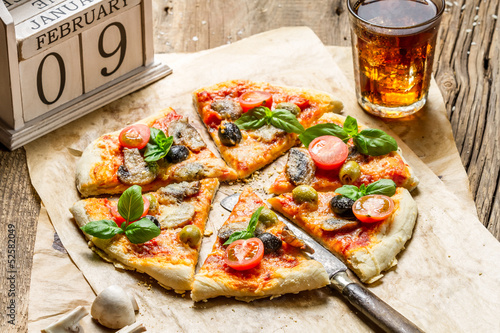 Baked pizza with old wooden calendar and cold drink