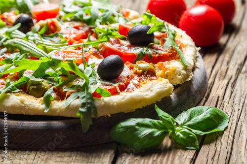 Closeup of freshly baked pizza with basil and tomatoes