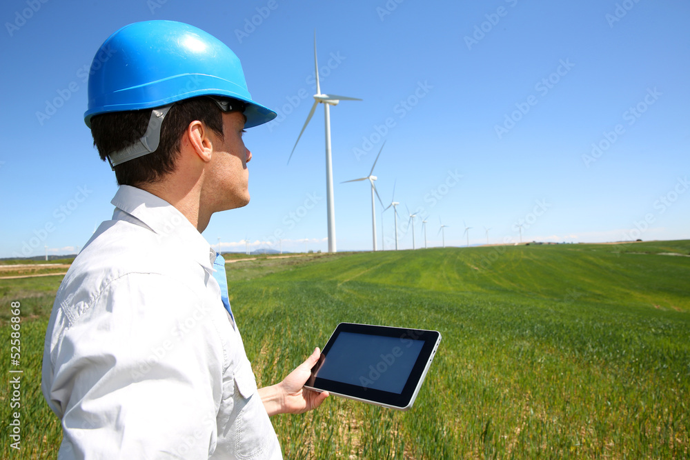 Businessman checking on wind turbine energy production Businessman checking on wind turbine energy production