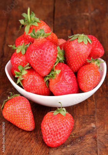 Fresh strawberry in bowl on wooden background