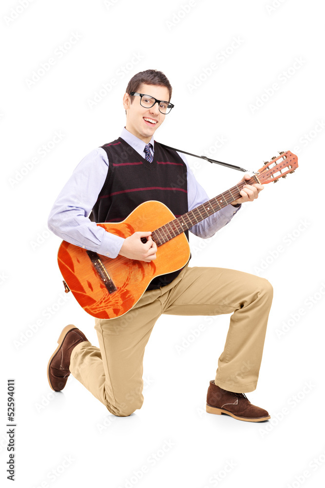 Young man playing an acoustic guitar and kneeling