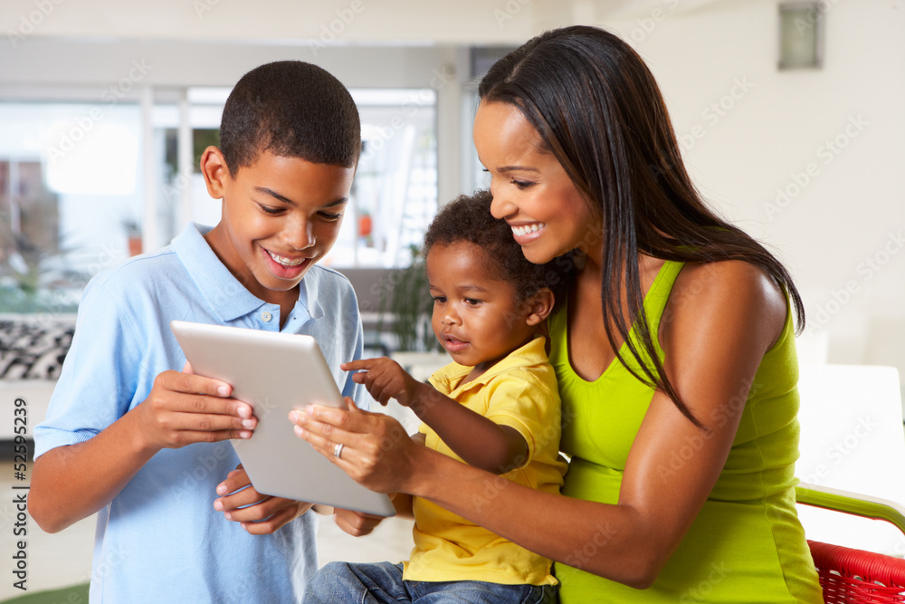 Mother And Children Using Digital Tablet In Kitchen Together