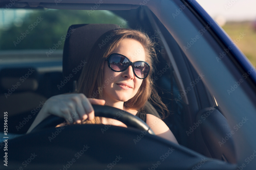 Beautiful businesswoman in sunglasses driving in the car