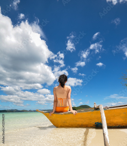 beautifl young bikini girl sitting on  tip of a boat on beach photo