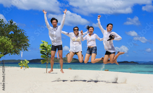 Two happy young couples jump together on tropical white beach