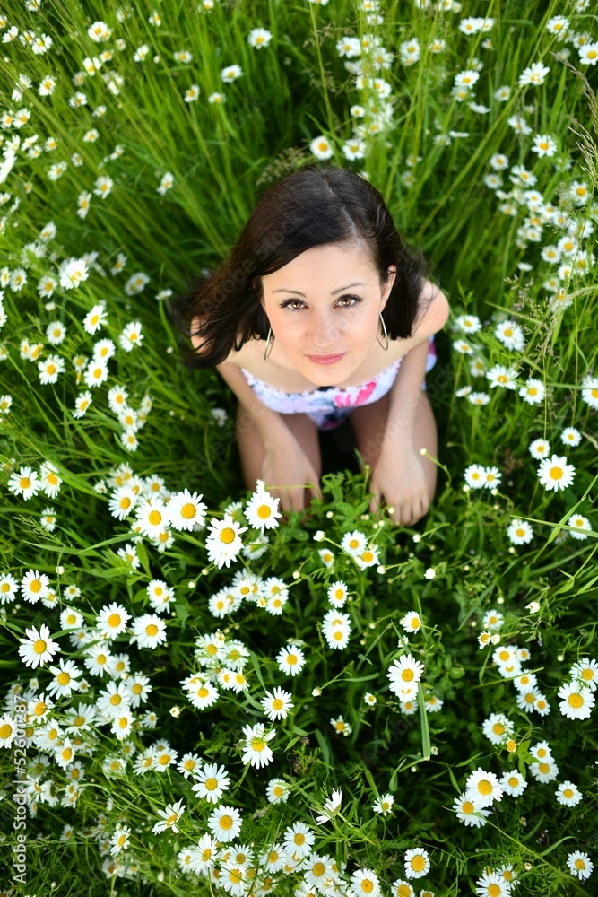 Young beautiful girl laying on the daisy flowers field Young beautiful girl laying on the daisy flowers field