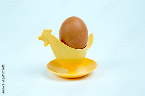 Brown egg in a hen or rooster shaped eggcup
