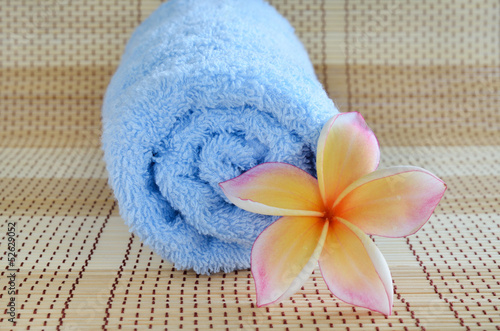 blue towel and plumeria flower on wooden background