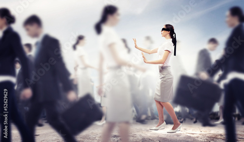 Businesswoman in blindfold among group of people photo