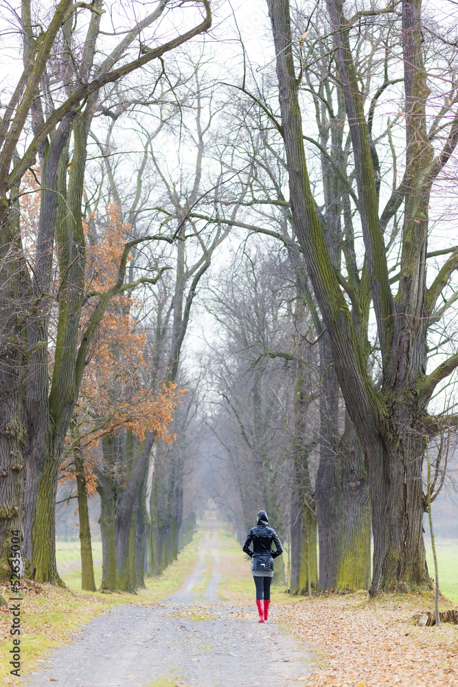 woman wearing rubber boots in autumnal alley