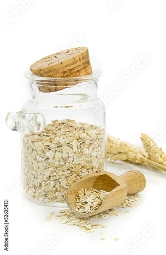 A jar of oatmeal flakes and wheat on a white background