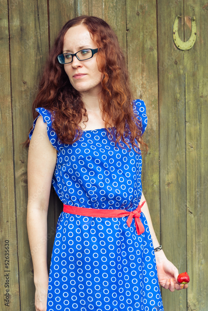 Obraz premium Red-haired girl holding a strawberry.