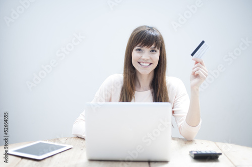 Portrait of beautiful, young woman using a laptop while holding 