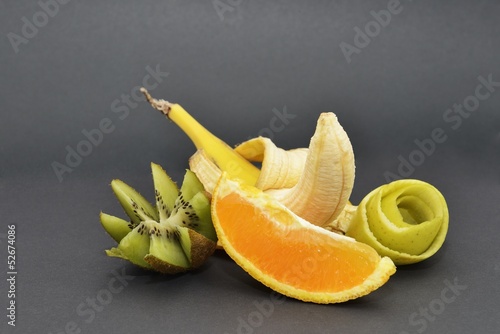 Банан, киви, апельсин и яблочная кожура на черном фоне