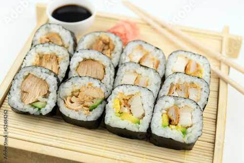Breaded and teriyaki chicken sushi on bamboo tray against white
