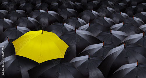 many blacks umbrellas and one yellow umbrella
