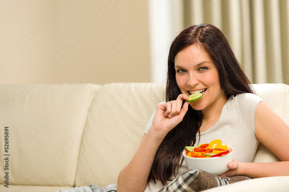 Woman sitting on sofa eating mixed salad Woman sitting on sofa eating mixed salad