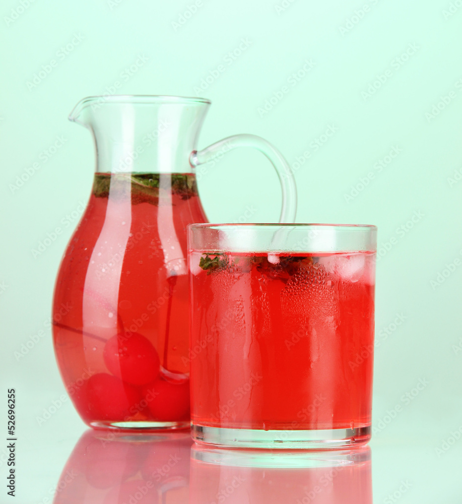 Cherry drink in pitcher and glass on green background. Cherry drink in pitcher and glass on green background.