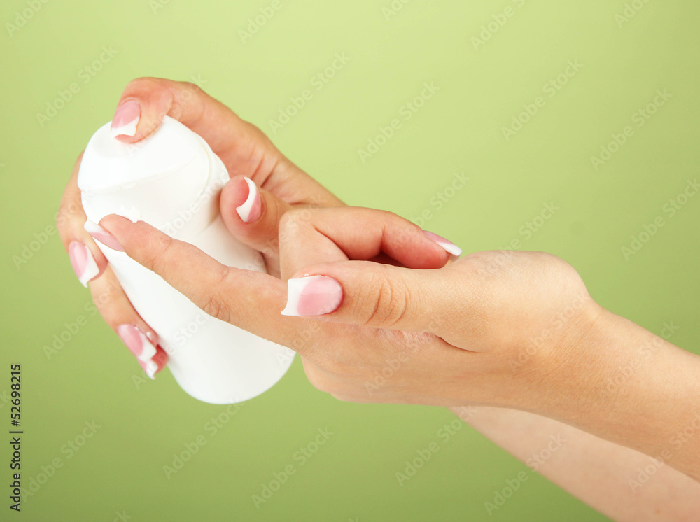 Woman applying cream on hands on color background Woman applying cream on hands on color background