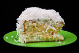 coconut cake piece on green plate isolated on black