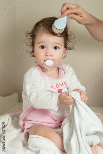 Mother combing her baby girl's hair with hairbrush after shower