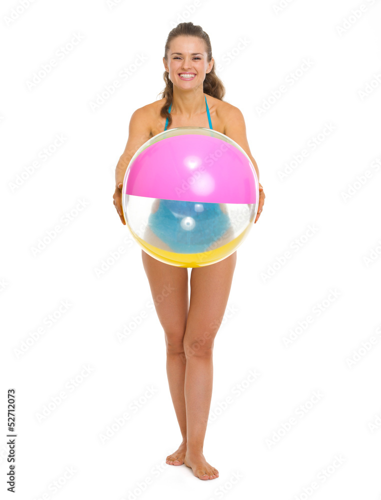 Full length portrait of woman in swimsuit giving beach ball Full length portrait of woman in swimsuit giving beach ball