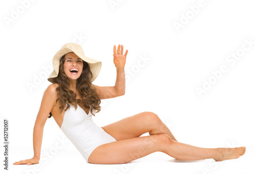Happy woman in swimsuit and hat laying on floor and greeting © Alliance