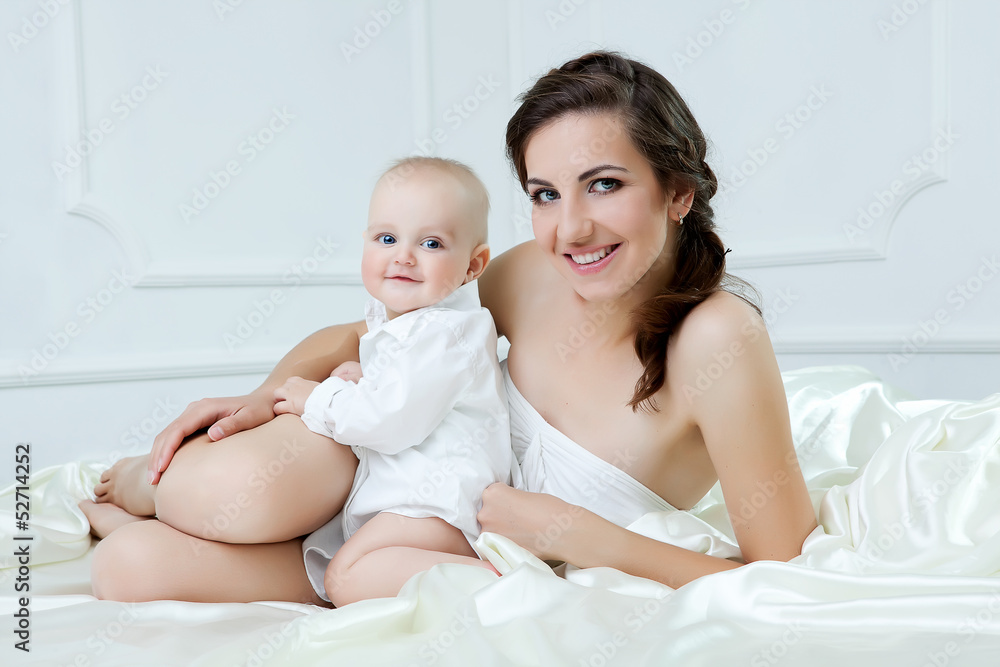 Happy family. Mother and her baby son playing and smiling on bed Happy family. Mother and her baby son playing and smiling on bed