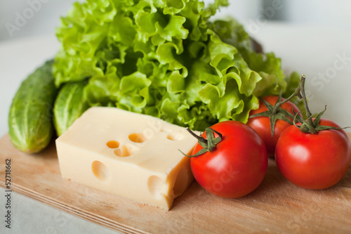 cheese and vegetables for salad on wooden board in the kitchen